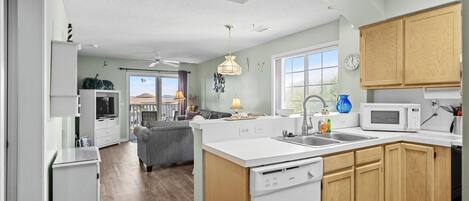 A modern kitchen with a dishwasher, microwave, and wooden cabinets.