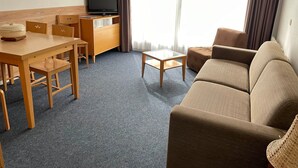 A hotel room with a wooden dining table, chairs, a sofa, a TV, and a window with curtains. - Gourette Studio 4 pers, Slope View, WIFI, Pets (Gourette)