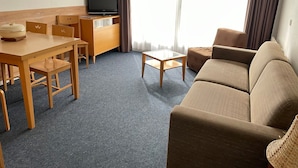A hotel room with a wooden dining table, chairs, a sofa, a TV, and a window with curtains. - Gourette Studio 4 pers, Slope View, WIFI, Pets (Gourette)