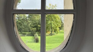 Ein Fenster mit Blick auf eine grüne Landschaft und Bäume.