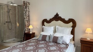 Ein Hotelzimmer mit Bett, Holz-Kopfteil, Duschbereich und zwei Nachttischlampen.