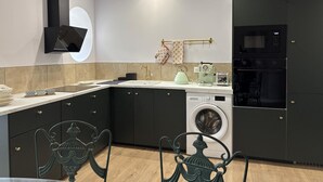 Eine moderne Küche mit dunklen Schränken, einer integrierten Waschmaschine und einem großen, schwarzen Kühlschrank.