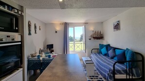 Ein kompakter Wohnraum mit Küchenzeile, Essbereich, Sofa und einem Balkon mit Blick.