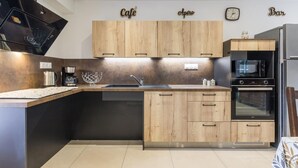 Eine moderne Küche mit Holzausstattung, Backofen, Mikrowelle und einer Kaffeemaschine.