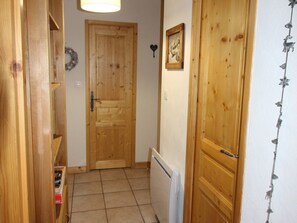A wooden door with a simple latch, a small framed picture on the wall, and a decorative garland. - 2-bedroom apartment, ski-in/ski-out, parking, sleeps 6 (Les Carroz d'Arâches)