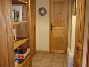 A wooden hallway with a door, a shelf with books, and a wreath on the wall. - 2-bedroom apartment, ski-in/ski-out, parking, sleeps 6 (Les Carroz d'Arâches)