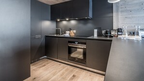Una cocina moderna con armarios oscuros, techo de madera y horno empotrado.