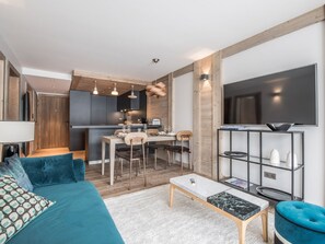 A modern living room with a sofa, coffee table, and TV. - Apartment in Courchevel Village center with WiFi (Courchevel 1550)