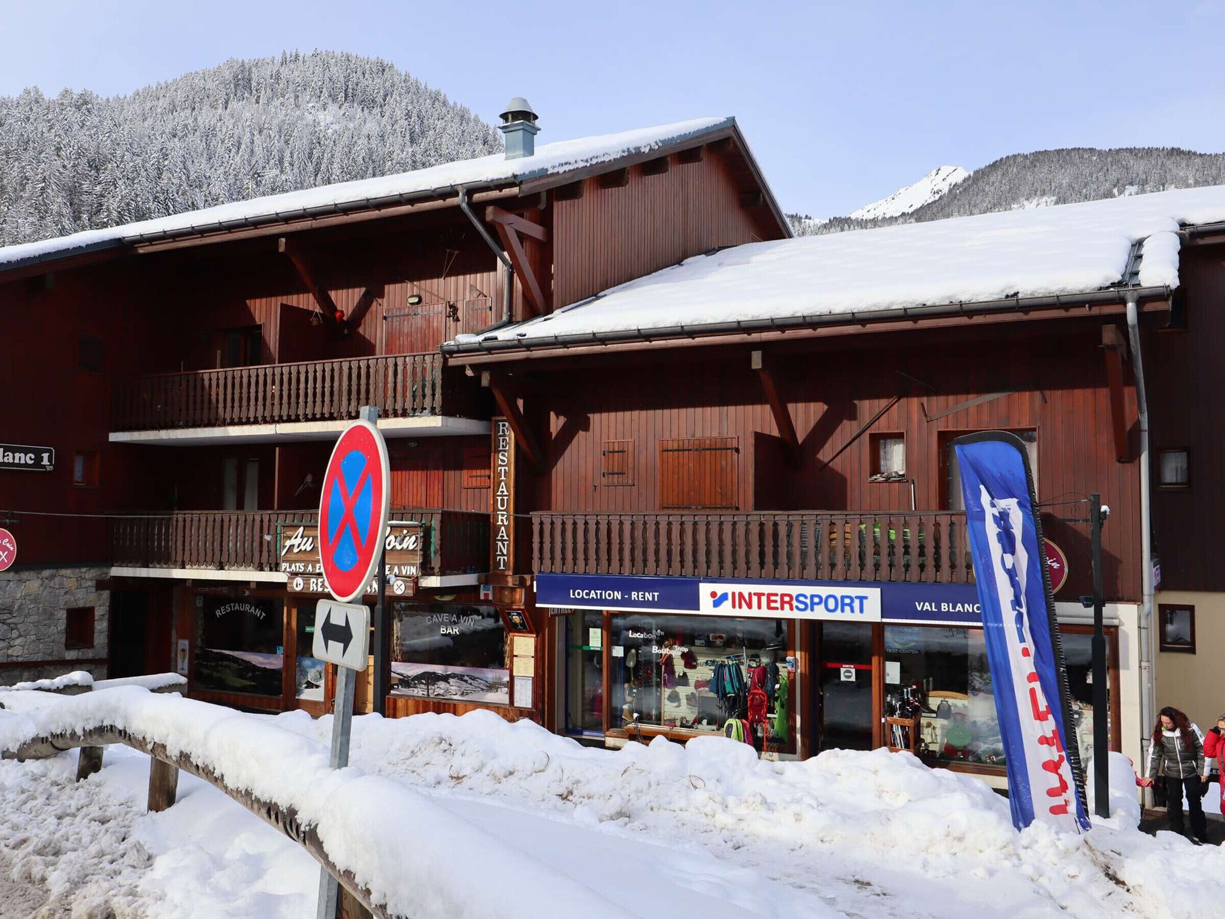 Ein Holzgebäude mit einem Restaurantschild, einem Hinweisschild für den Standort und Mietpreise sowie einer Flagge.