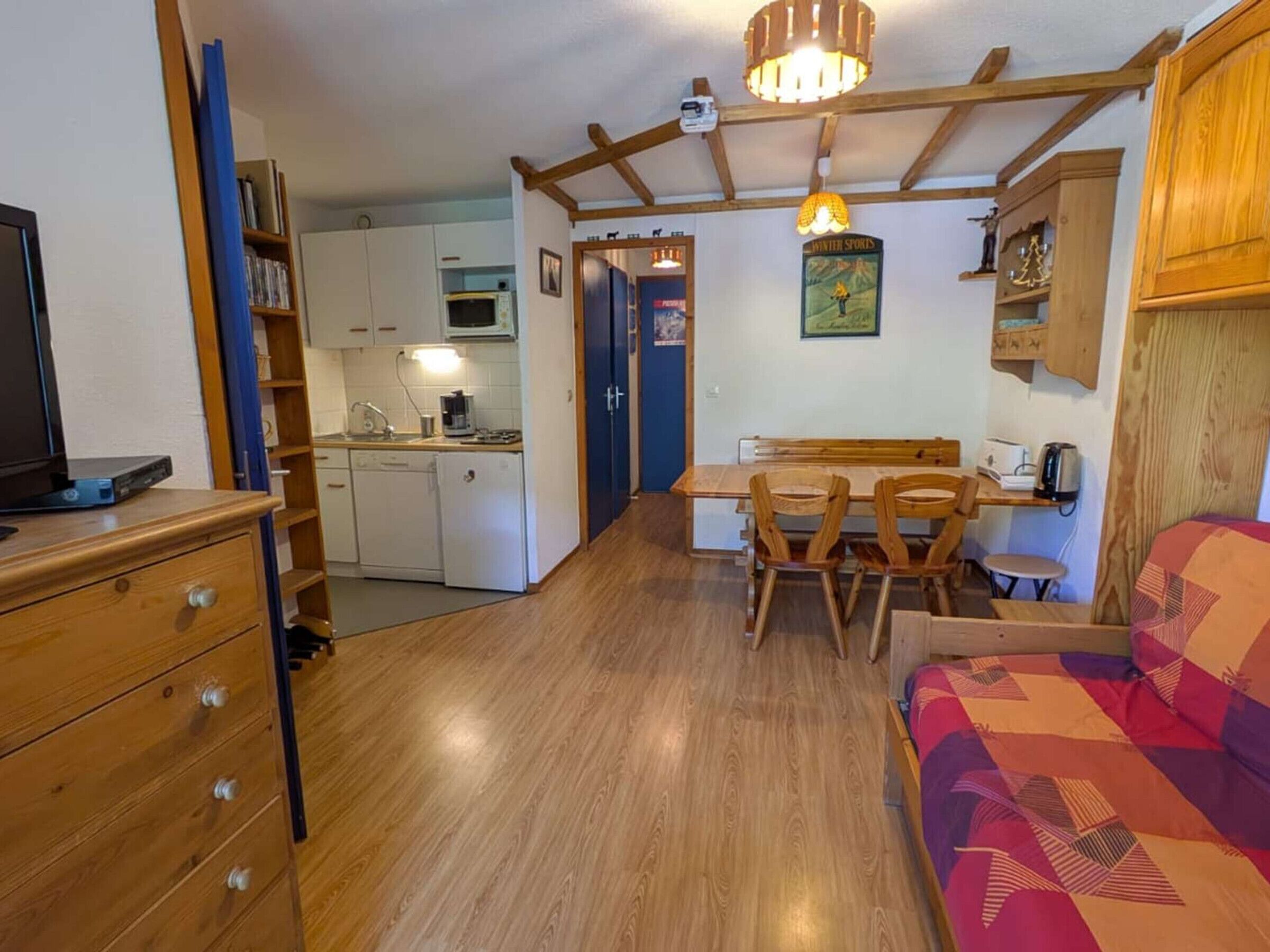 Um espaço compacto com cozinha compacta, área de refeições e uma cama.