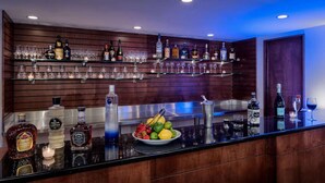 A bar area with shelves of liquor bottles and glasses, a fruit bowl, and a candle on the counter. - Close to PHL Airport + Dining. Pool. Free Shuttle. (Philadelphia)