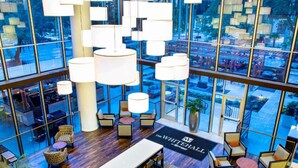 Eine geräumige Lobby mit hoher Decke, moderner Möblierung und großen Fenstern mit Blick auf die Stadt.