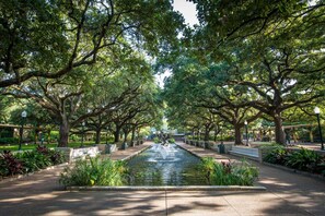 A park with a central water feature, surrounded by trees and benches. - Near Theater District | Pool. Free Shuttle. Dining (Houston)