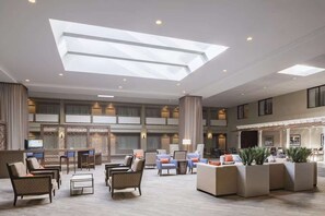 A spacious lobby with a high ceiling, multiple seating areas, and a large skylight. - Close to Laurel Park with On-site Dining & Gym (Laurel)