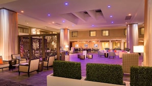 Eine großzügige Hotelhalle mit hoher Decke, verschiedenen Sitzbereichen und einer Rezeption.