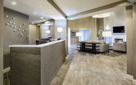 A hotel lobby with a reception desk, seating area, and a fireplace.