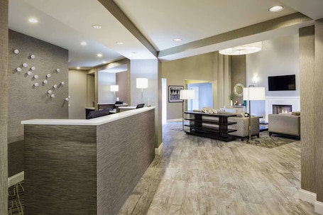 A hotel lobby with a reception desk, seating area, and a fireplace.