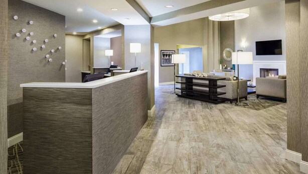 A hotel lobby with a reception desk, seating area, and a fireplace.