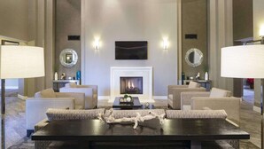 A modern living room with a fireplace, two sofas, a coffee table, and decorative mirrors.