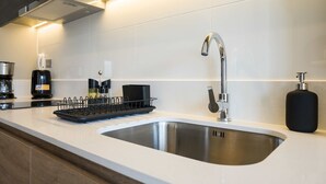 Eine moderne Küche mit Spüle aus Edelstahl, einer Kaffeemaschine und einem Geschirrgestell.