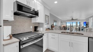 Una cocina moderna con armarios blancos, una campana extractora de acero inoxidable y un horno empotrado.