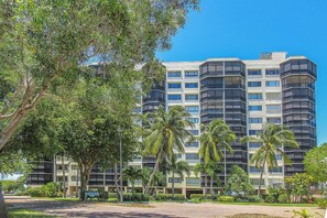 A multi-story hotel with balconies, surrounded by palm trees and greenery. - 2B/2B HARBOUR POINTE CONDO 816S ON THE BAY, WATCH THE BOATS GO BY, FISHING DOCK, WALK TO BEACH! (Fort Myers Beach)