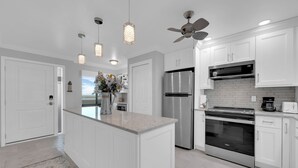 Una cocina moderna con armarios blancos, electrodomésticos de acero inoxidable e iluminación colgante.
