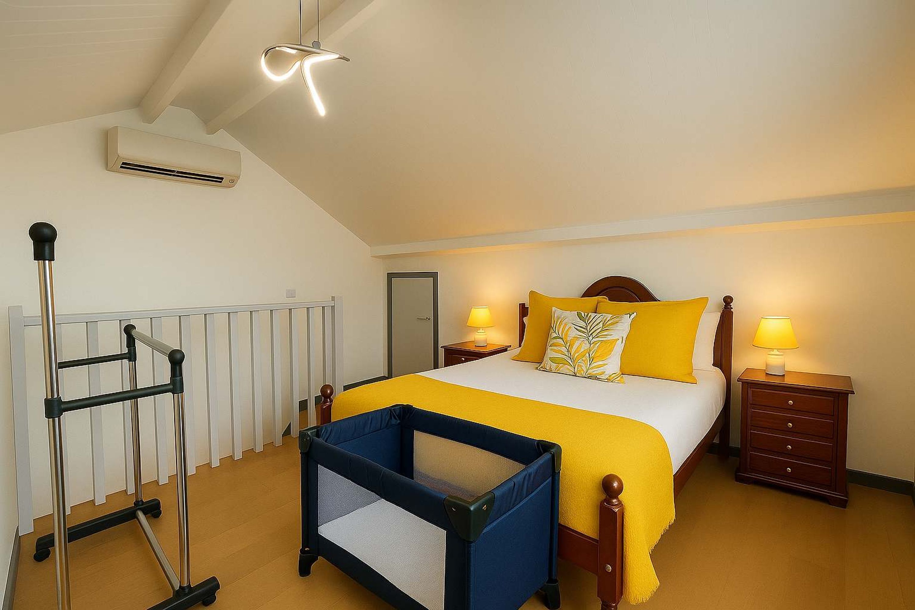 Ein Schlafzimmer mit einem Bett, einem Nachttisch, einem Beistelltisch, einem Babybett und einer Klimaanlage.
