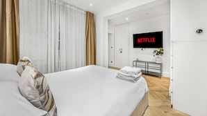 Een moderne hotelkamer met een groot bed, een flatscreen televisie aan de wand en een houten vloer.