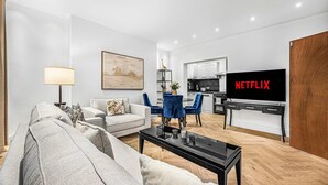 Een moderne woonkamer met een grijze bank, een salontafel en een tv waarop 'NETFLIX' staat.