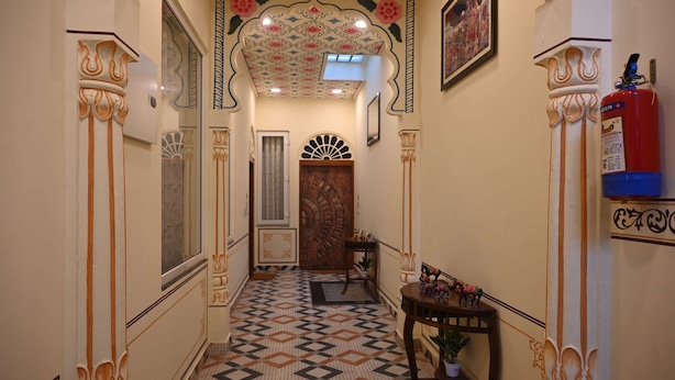 A hallway with ornate columns, patterned floor tiles, and a decorative ceiling. - Hotel Virasat Haveli (Sawai Madhopur)