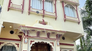 A traditional building with ornate balconies, a large wooden door, and decorative elements. - Hotel Virasat Haveli (Sawai Madhopur)