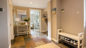A hallway with a white bench, a shoe rack, and a door leading to another room.