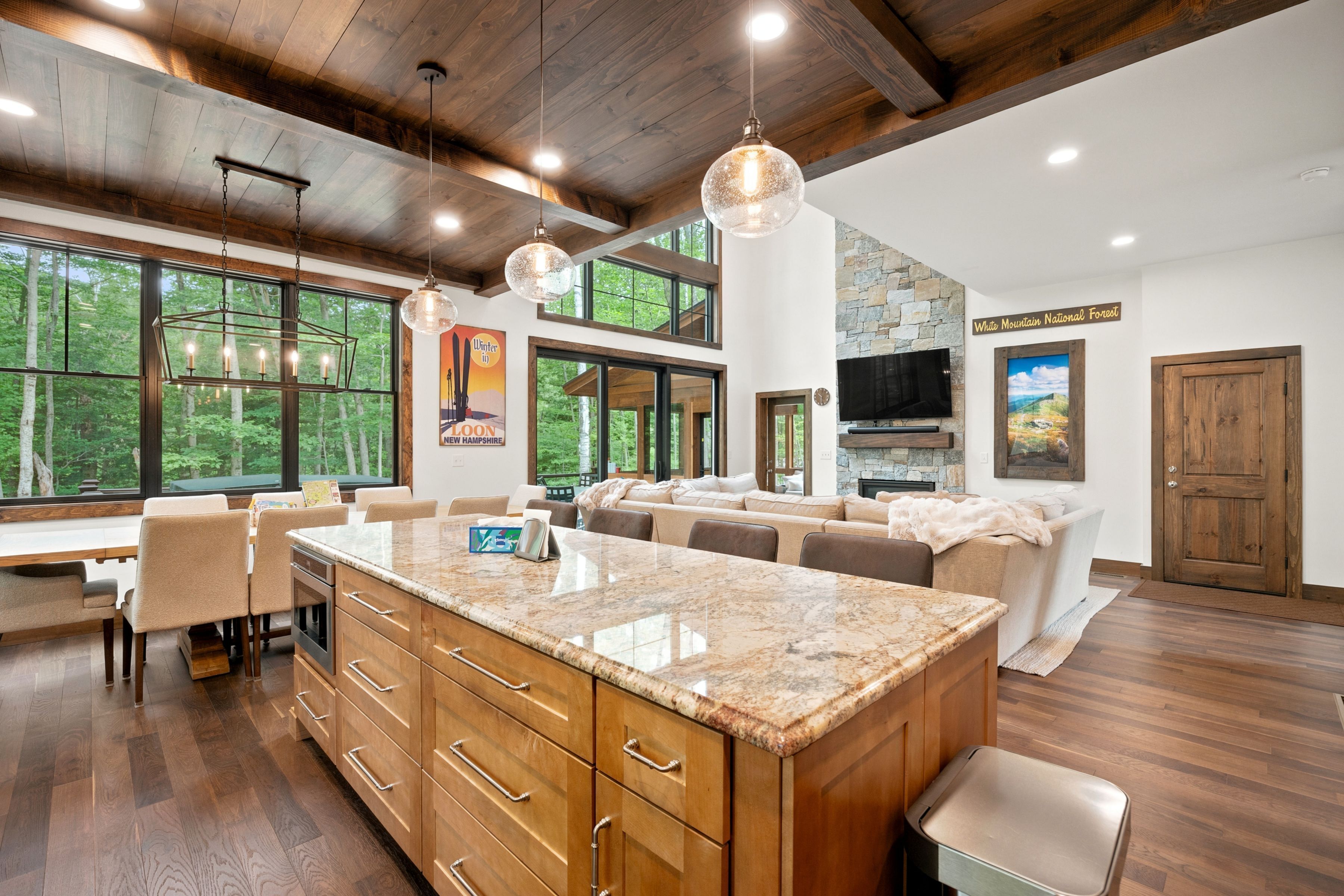 A spacious kitchen with a large island, wooden cabinetry, and a stone fireplace.