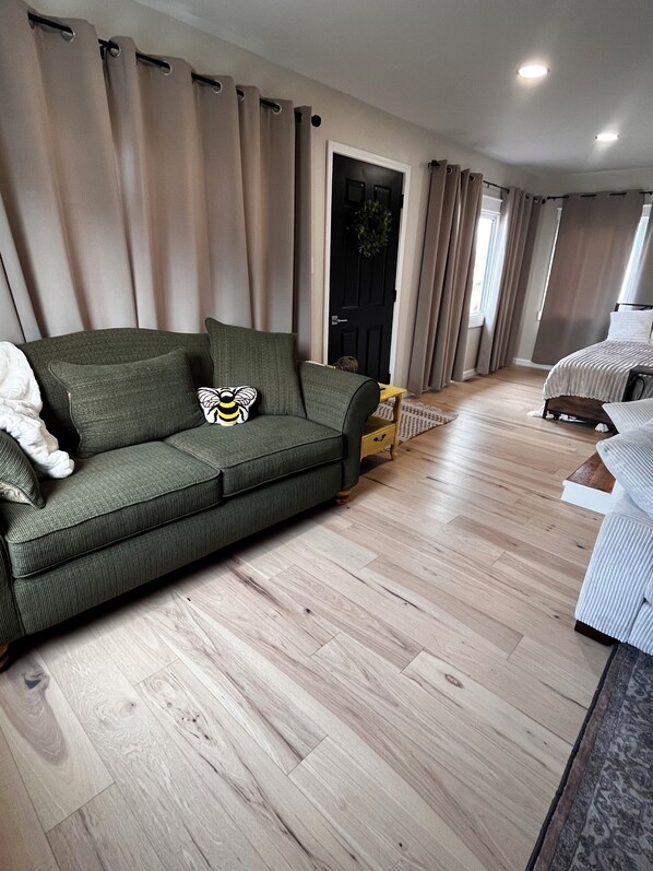 Una sala de estar moderna con un sofá verde, un sillón blanco y piso de madera.