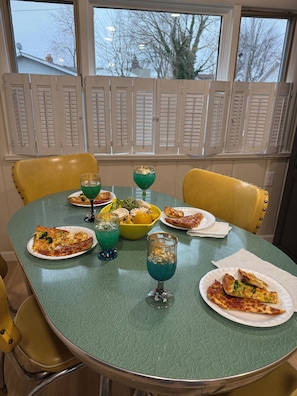 A dining table with pizza, a yellow bowl, and two glasses of blue liquid. - Charming 4-bedroom home with private beach park. Large patio and driveway. (Huron)