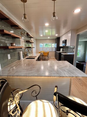 Una cocina moderna con una isla central, iluminación colgante y vistas al exterior.