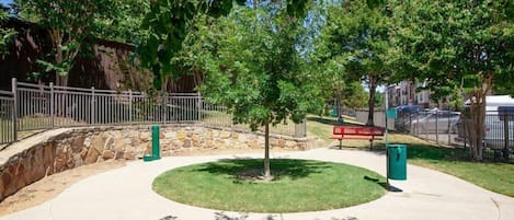 A park with a circular walking path, a bench, and a stone wall.