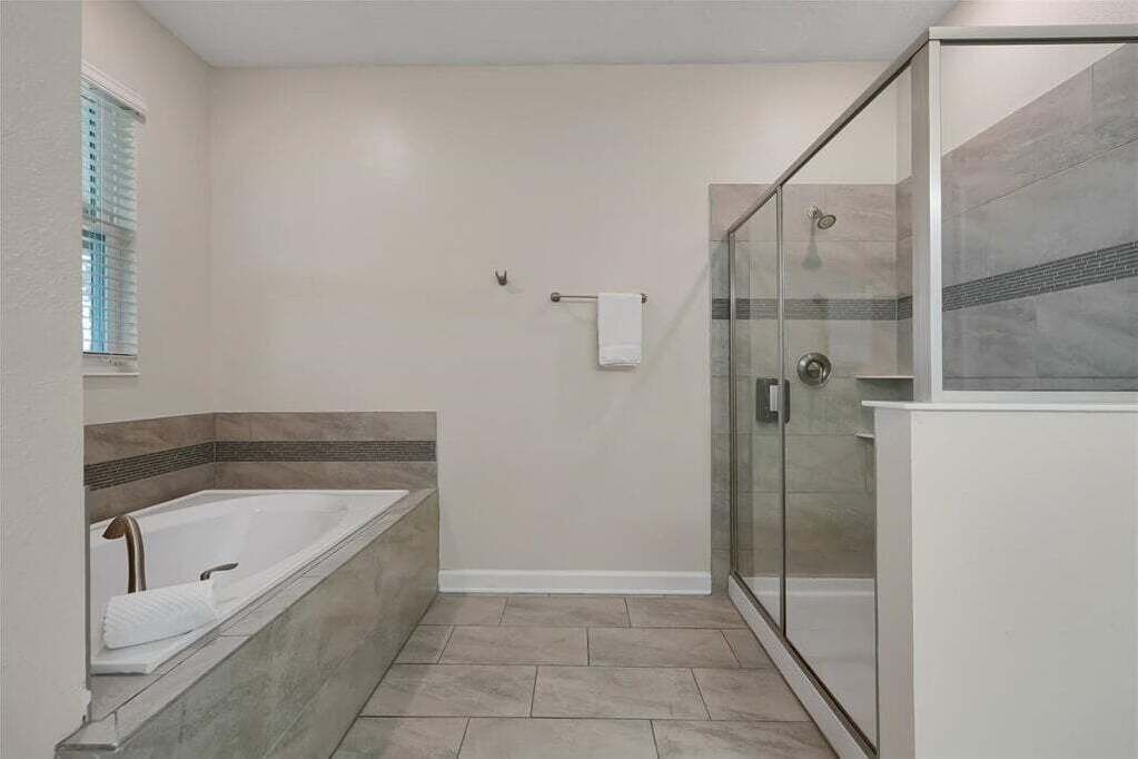 A bathroom with a bathtub, a glass shower enclosure, and a towel rack.