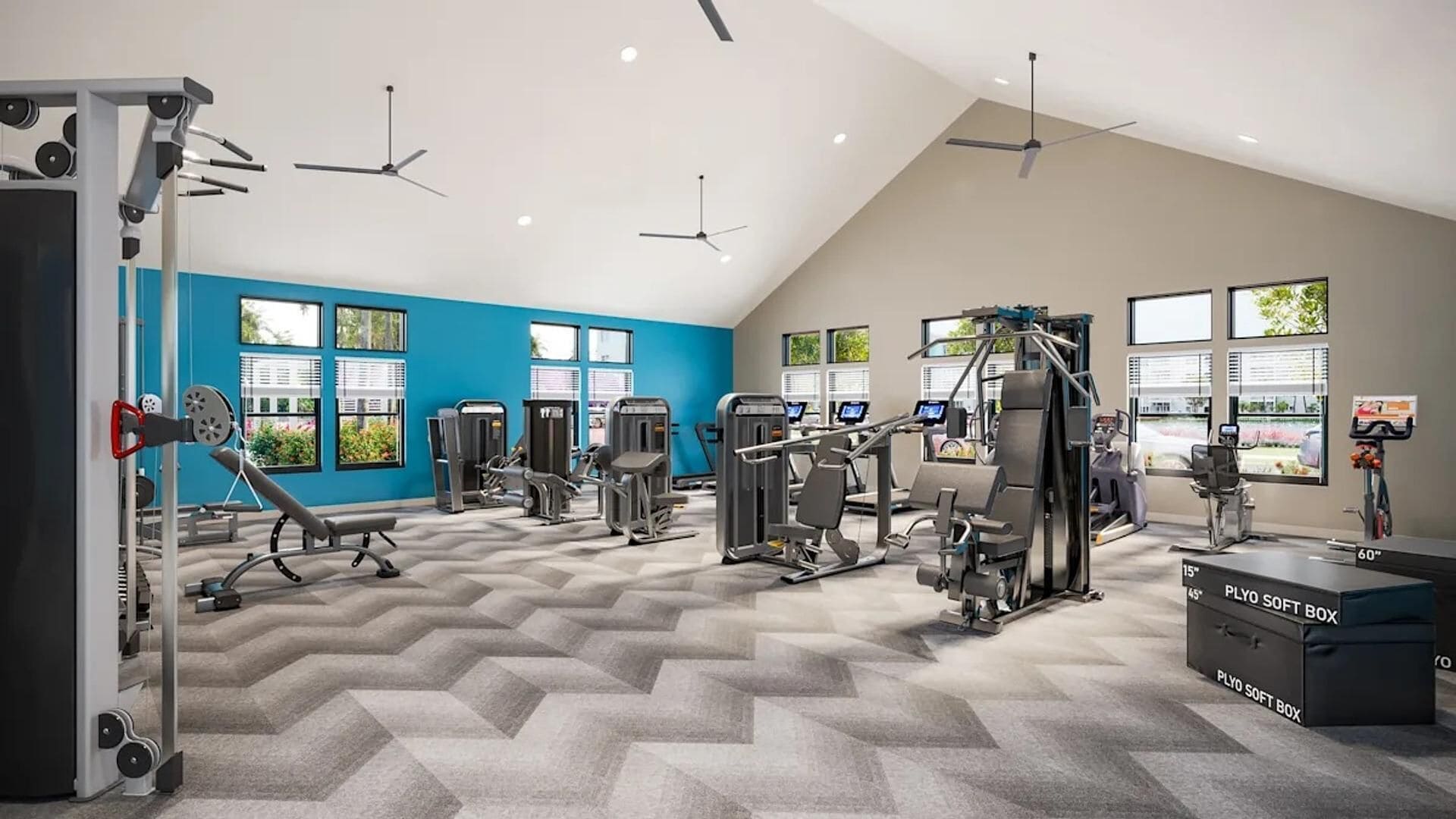 A modern gym with various exercise machines, large windows, and a high ceiling.