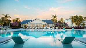 Una piscina con lettini e un edificio a tetto piatto sullo sfondo.