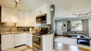 A modern kitchen with stainless steel appliances, white cabinetry, and a central island. - Furnished Patio! Suburban Gem 11 Mi to Dtwn Denver (Arvada)