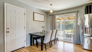 A dining area with a table and chairs, a refrigerator, and a view through a glass door to an outdoor patio. - Furnished Patio! Suburban Gem 11 Mi to Dtwn Denver (Arvada)