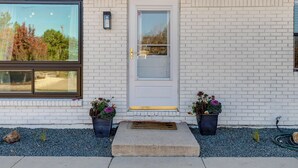 A white brick building with a white door, two potted plants, and a window. - Furnished Patio! Suburban Gem 11 Mi to Dtwn Denver (Arvada)