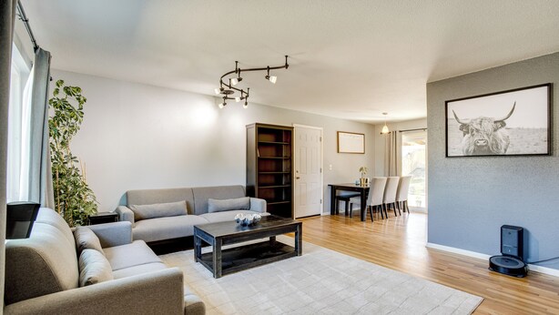 A modern living room with a sofa, a coffee table, and a dining area with chairs and a table. - Furnished Patio! Suburban Gem 11 Mi to Dtwn Denver (Arvada)