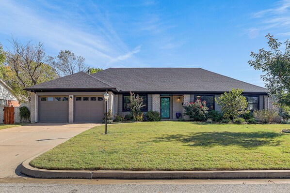 A two-story house with a grey roof, a front garage, and a well-maintained lawn. - Pet-friendly Home w/ Yard: 8 Mi to Downtown Tulsa! (Tulsa)