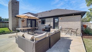Eine Terrasse mit einer eingebauten Couch, einem Grill und Gartenmöbeln.