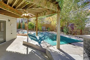 A covered patio area with a pool, wooden beams, and a ceiling fan. - 6 Mi to Barr Lake: Apt w/ Yard & Pool Access! (Brighton)