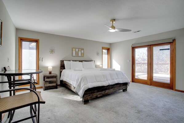 Une chambre à coucher avec un lit, un ventilateur de plafond, une table avec des chaises et une fenêtre.