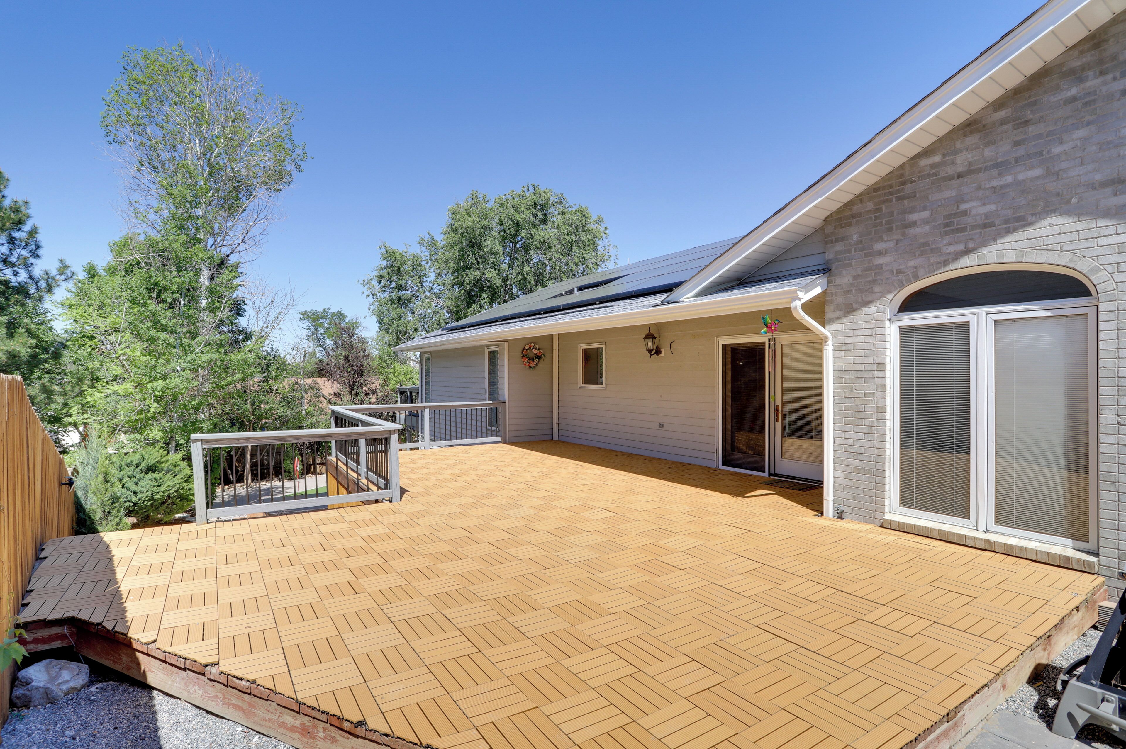 A house with a wooden deck, a covered patio, and a brick exterior.